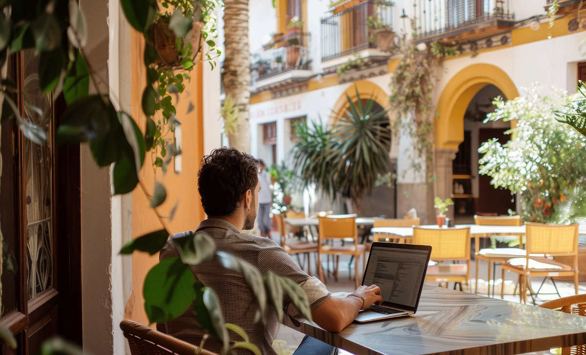 digital nomad expat working on laptop at cafe terrace or coworki Spain for Digital Nomads