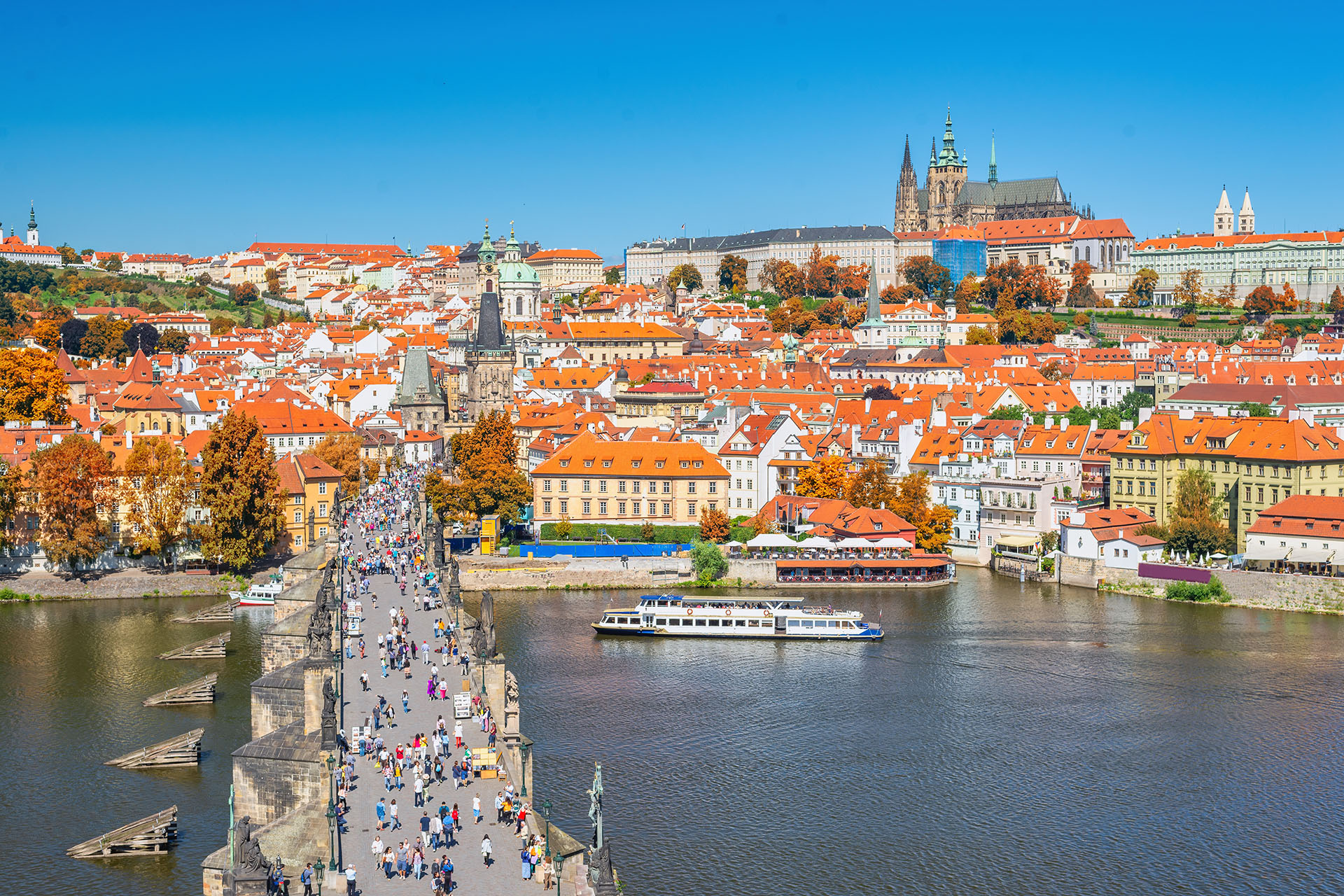 pedestrians streaming across Charles Bridge with Prague skyline