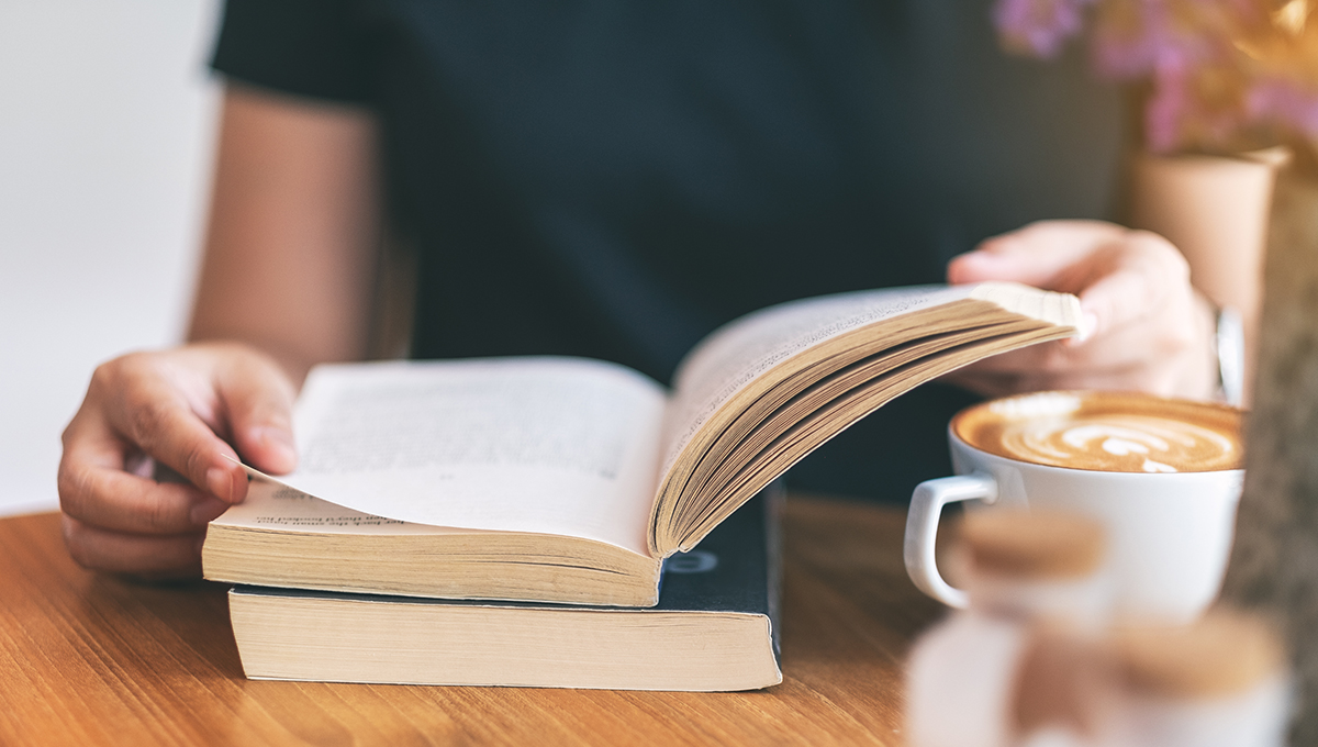 Closeup image of a woman holding and reading a vintage novel boo woman reading book